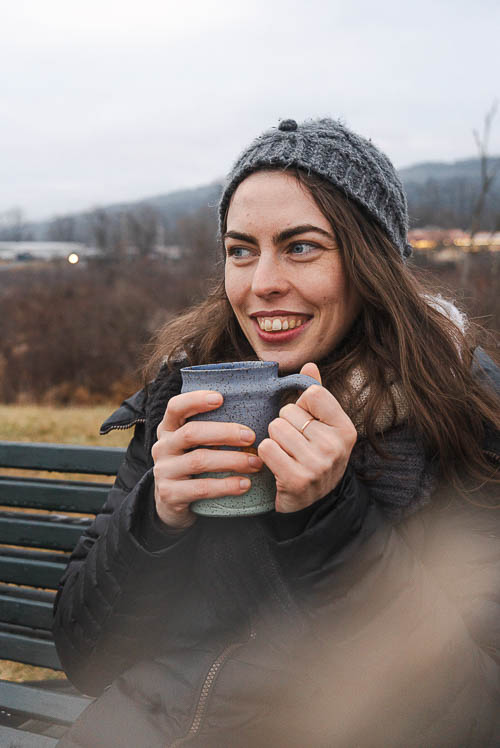 Portrait of woman sitting on bench with mug