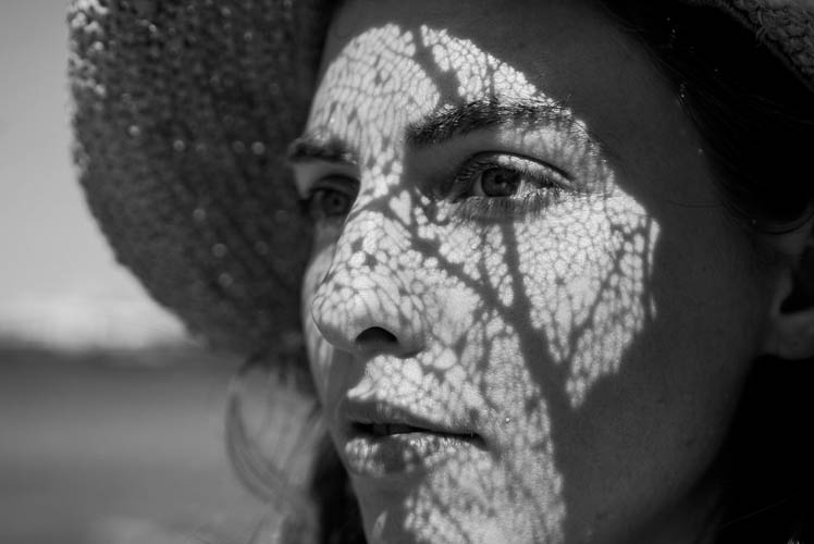 Portrait of woman in black in white with a shadow across her face